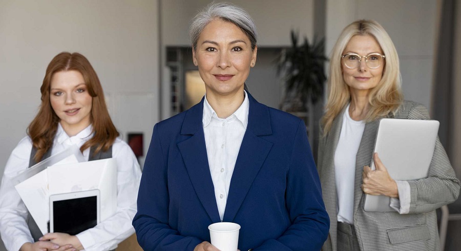 Three women of different ages dressed in business attire look confidently into the camera