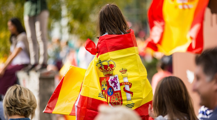 Image: Jorge Sanchez Photos/Shutterstock Young girl in a crowd with the Spanish draped over her back