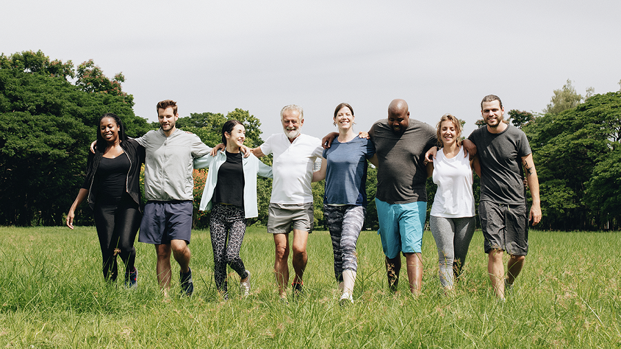 Shutterstock / Rawpixel.com A group of smiling people walking across a field with arms around each others' shoulders