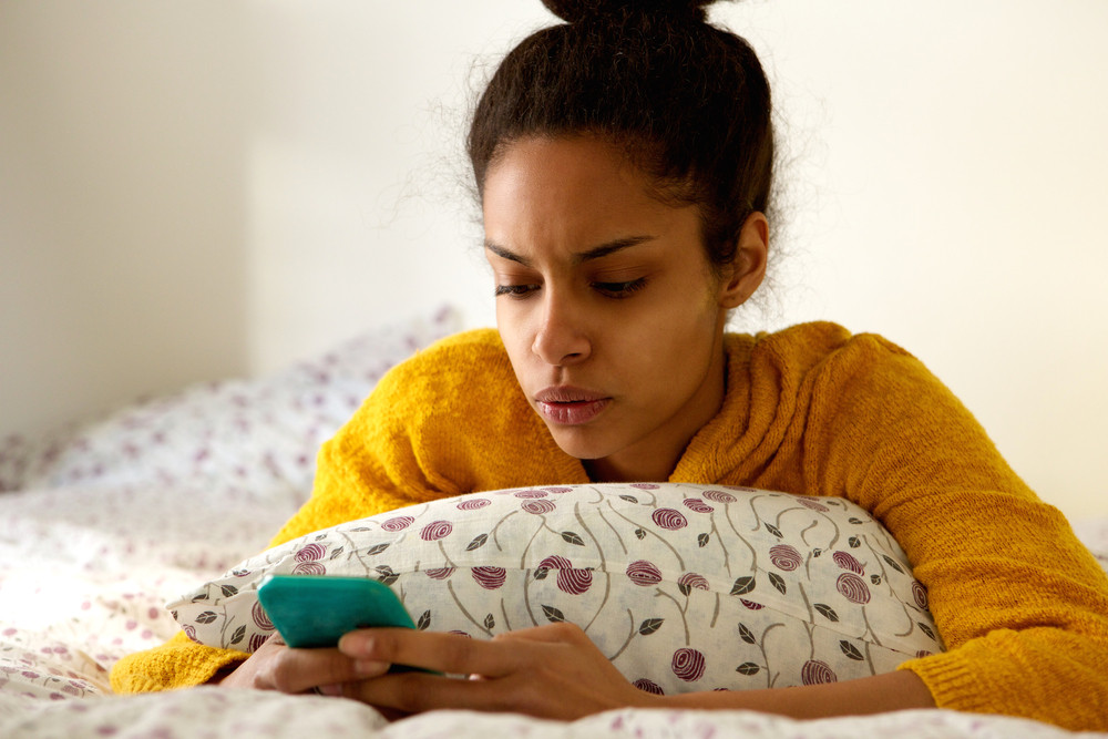 Close up portrait of a worried young woman looking at phone